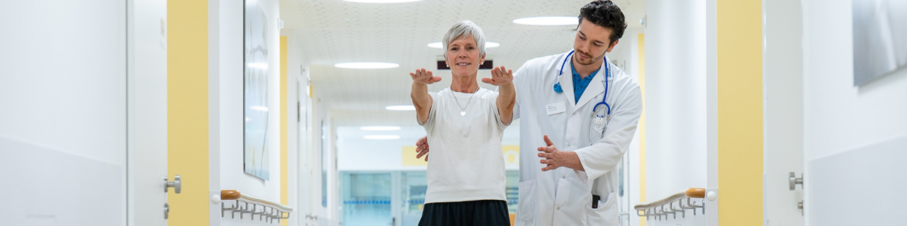 Patient and doctor shown in assisted walking as part of the rehabilitation after a stroke