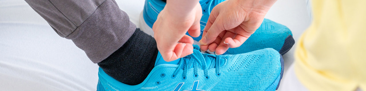 Nurse helping a patient tie their shoes during their neurological rehabilitation stay