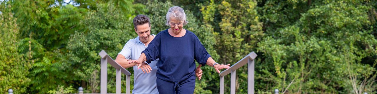 Multiple Sklerose-Patientin zusammen mit einem Physiotherapeut im Park der Rehaklinik Zihlschlacht