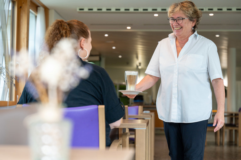 Besucherin und Hotellerie-Mitarbeiterin im Café im Park