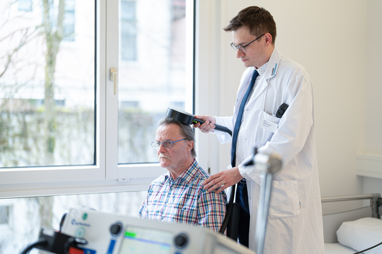 Neurologe und Patient während der repetitiven transkraniellen Magnetstimulation
